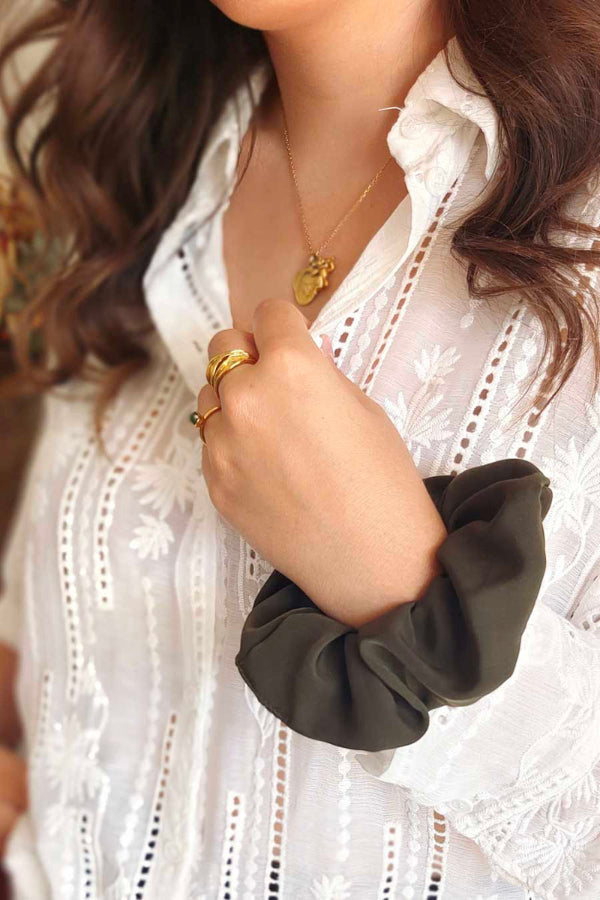Chouchou Kaki en gros plan au poignet sur une blouse blanche